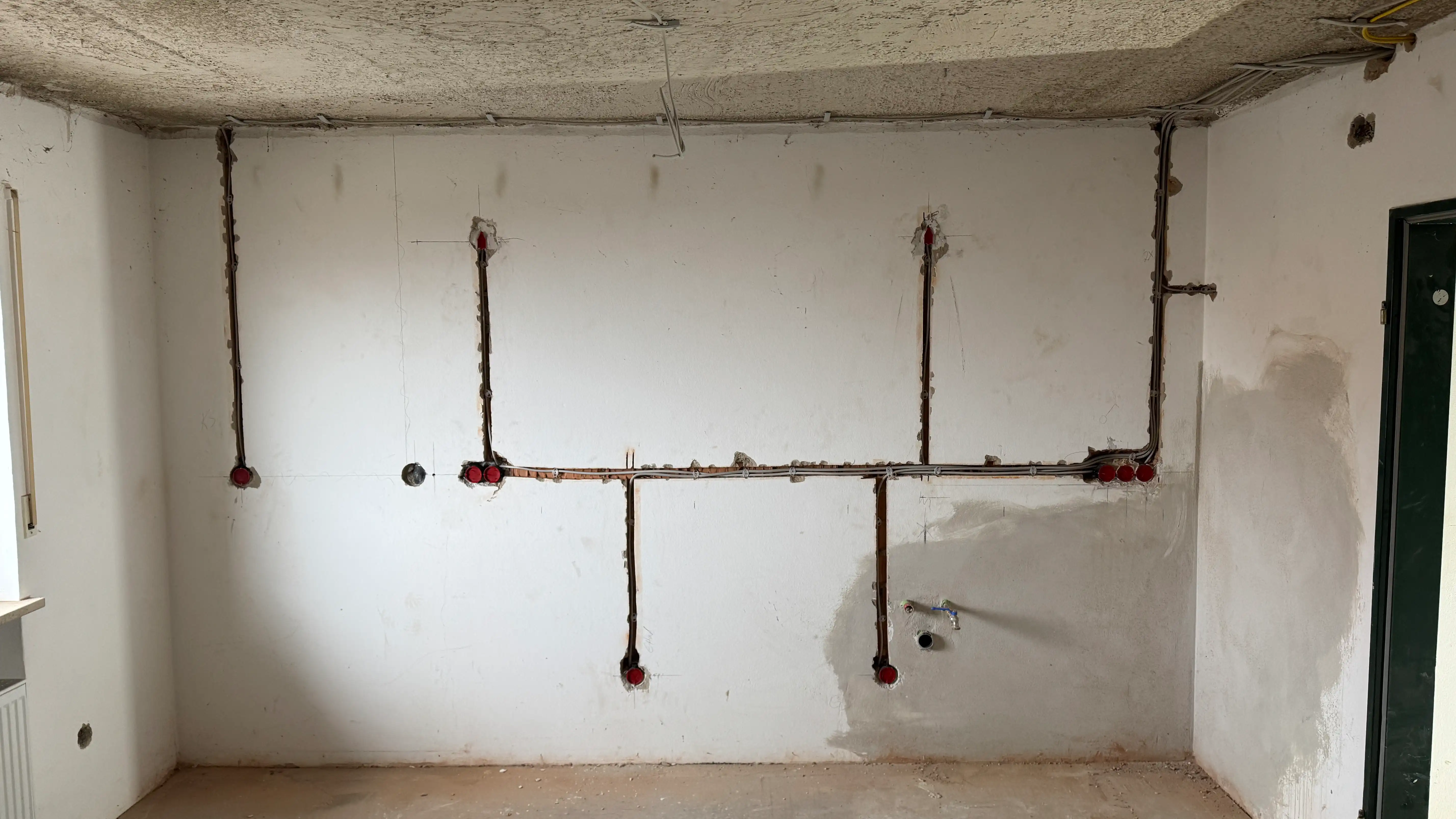 Rohbauinstallation einer Küche – Elektro- und Sanitärleitungen vorbereitet für Küchenmontage in Wohngebäude